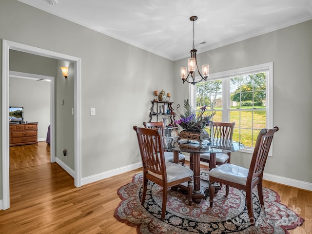 dining space with an inviting chandelier, light hardwood / wood-style floors, and crown molding