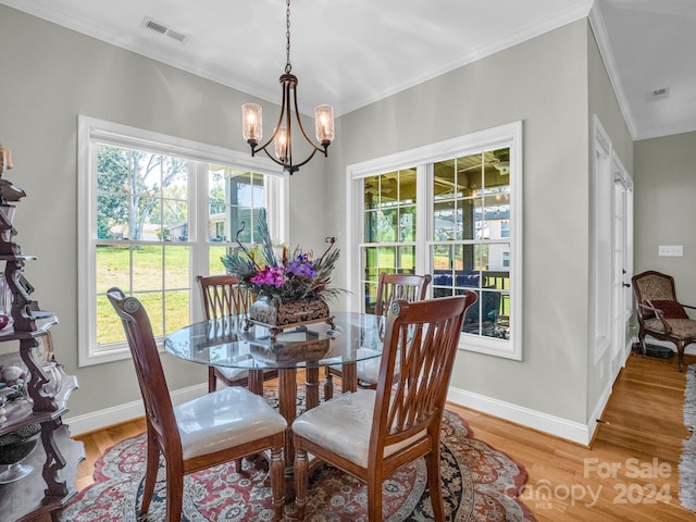 dining room with a chandelier, crown molding, and light hardwood / wood-style flooring