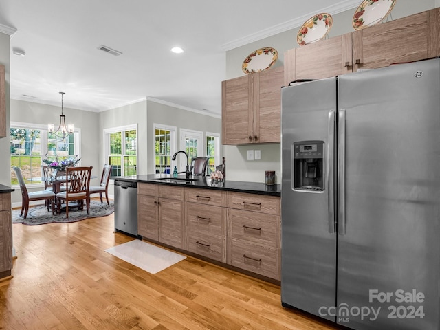 kitchen featuring light wood-type flooring, ornamental molding, a chandelier, sink, and appliances with stainless steel finishes