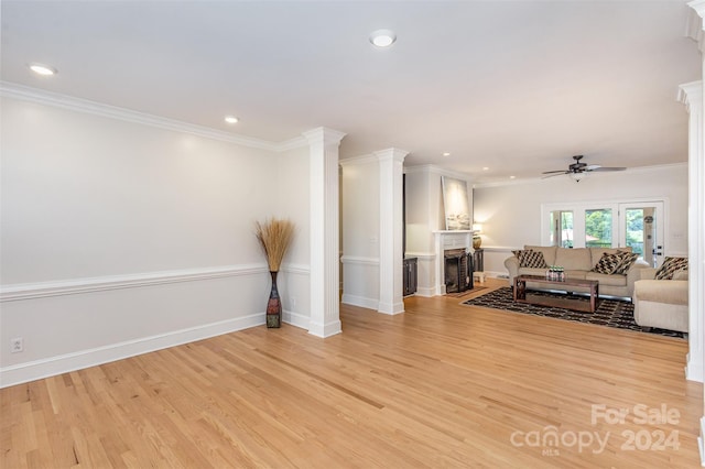 living area featuring light wood-style floors, a fireplace, and ornamental molding