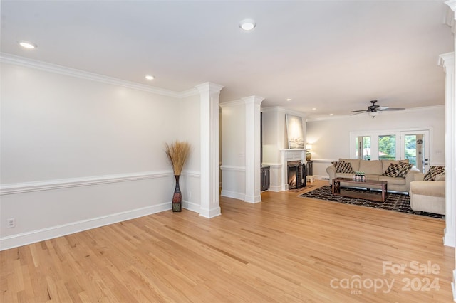 living area featuring a warm lit fireplace, ornamental molding, and light wood-type flooring