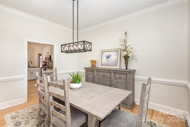 dining area with baseboards, light wood-type flooring, and crown molding