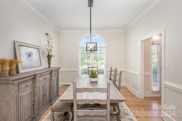 dining area featuring light wood finished floors, an inviting chandelier, a wealth of natural light, and crown molding