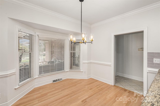 unfurnished dining area with ornamental molding, visible vents, light wood finished floors, and an inviting chandelier