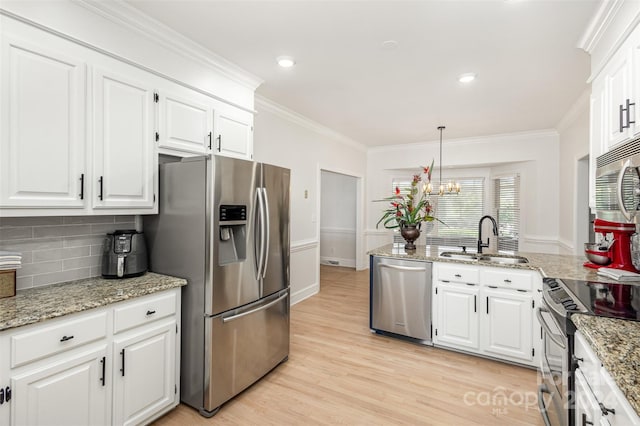 kitchen with stainless steel appliances, a sink, white cabinetry, light wood-style floors, and ornamental molding