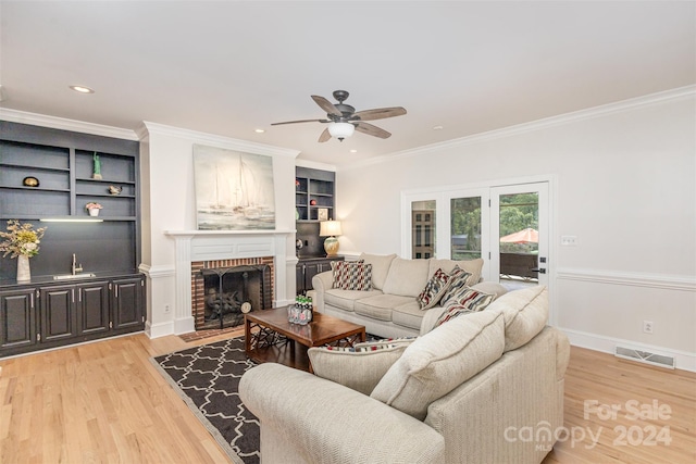 living room with visible vents, ornamental molding, light wood-type flooring, a fireplace, and recessed lighting