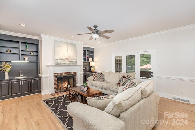 living room featuring light wood finished floors, visible vents, crown molding, a fireplace, and recessed lighting