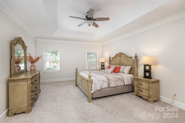 bedroom with light carpet, baseboards, a raised ceiling, a ceiling fan, and ornamental molding