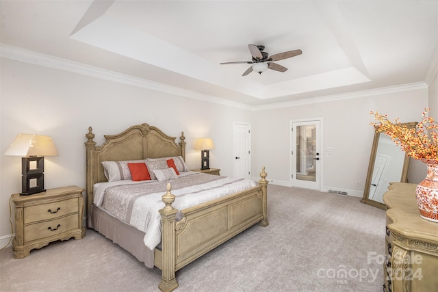 bedroom with light colored carpet, a ceiling fan, baseboards, a tray ceiling, and crown molding