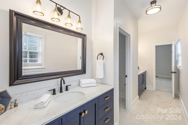 full bath with marble finish floor, vanity, and baseboards