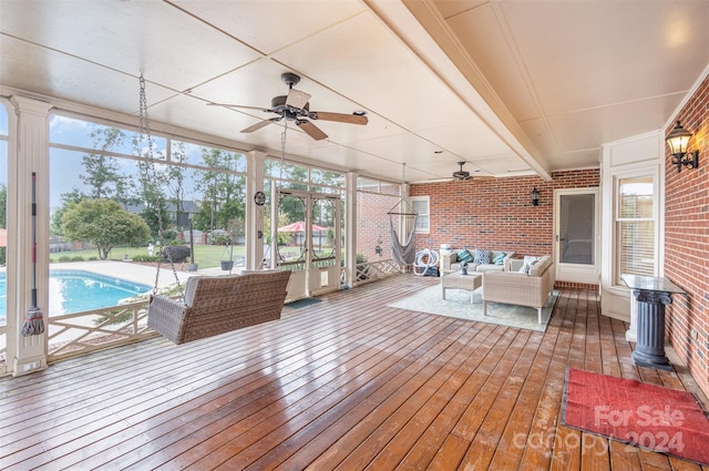 unfurnished sunroom featuring ceiling fan and beam ceiling