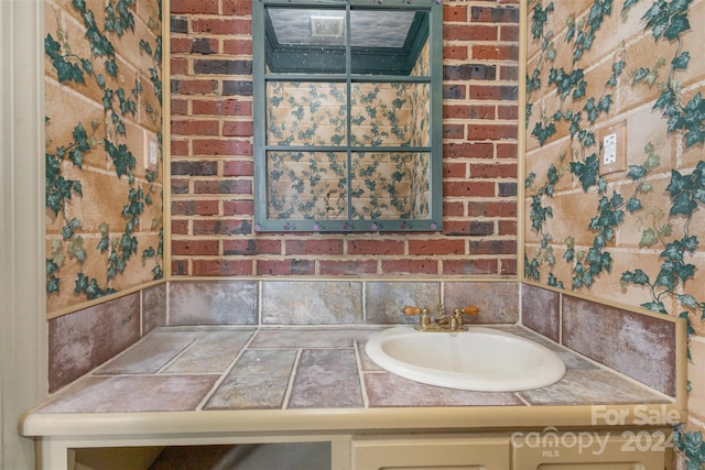 bathroom with brick wall and a sink