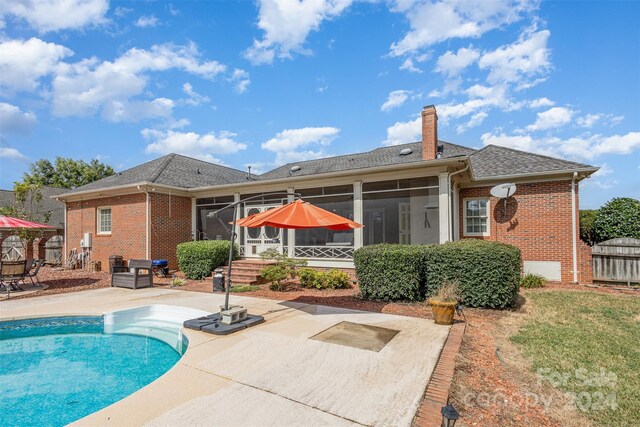 rear view of house featuring a sunroom, brick siding, and a patio