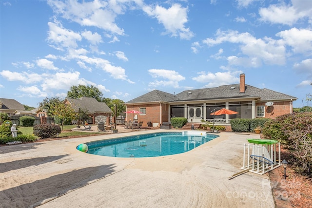 pool with a patio area, fence, and a sunroom