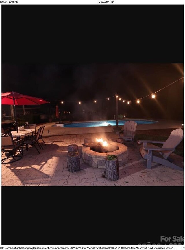 patio at night with a jacuzzi and an outdoor pool