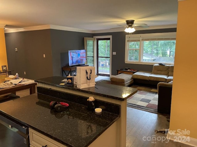 kitchen with a center island, hardwood / wood-style floors, dark stone counters, ceiling fan, and ornamental molding