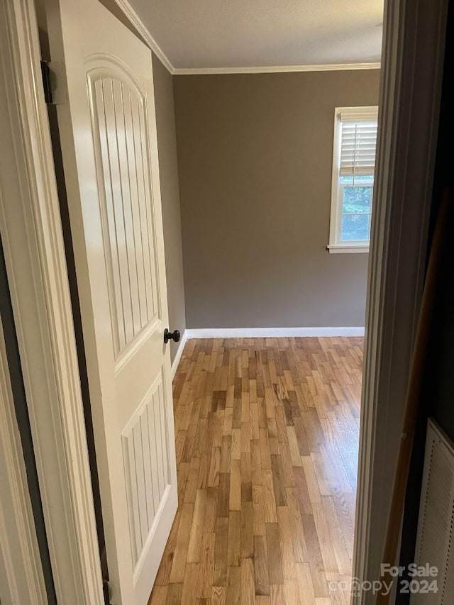 empty room with light hardwood / wood-style floors and crown molding