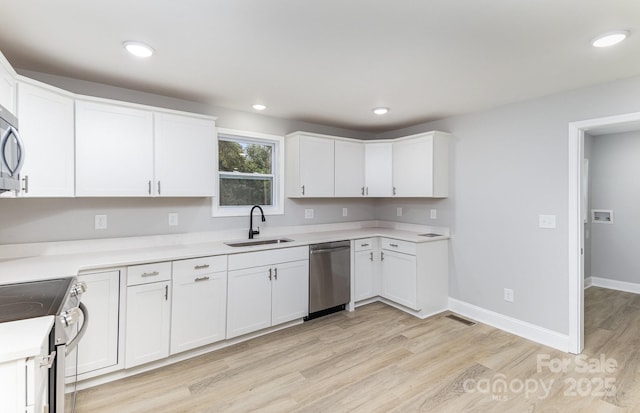 kitchen featuring white cabinetry, sink, stainless steel appliances, and light hardwood / wood-style floors