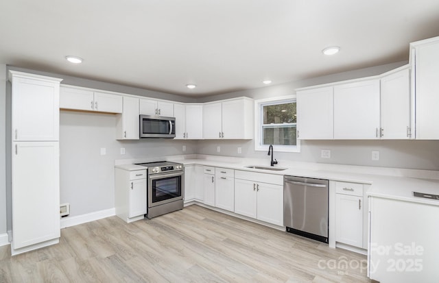 kitchen with sink, light hardwood / wood-style flooring, white cabinets, and appliances with stainless steel finishes