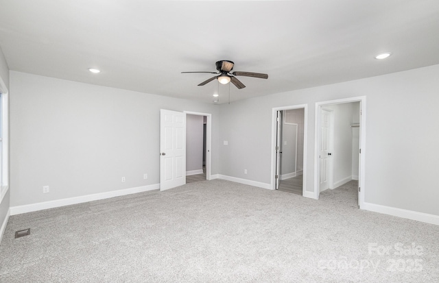 unfurnished bedroom featuring ceiling fan, a walk in closet, and light carpet