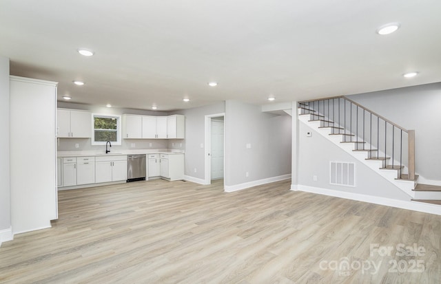 kitchen featuring dishwasher, sink, white cabinets, and light hardwood / wood-style flooring