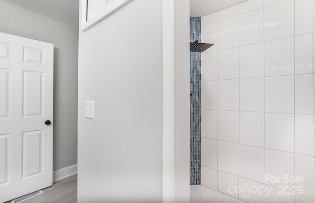 bathroom with a tile shower and hardwood / wood-style flooring