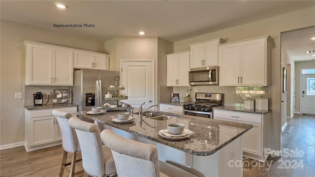 kitchen featuring hardwood / wood-style floors, stainless steel appliances, a kitchen island with sink, and sink