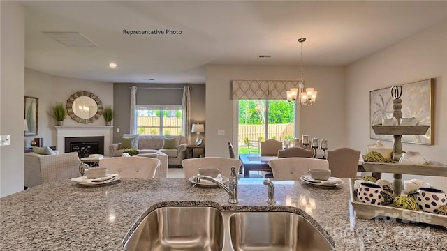 kitchen with a chandelier, sink, and stone counters