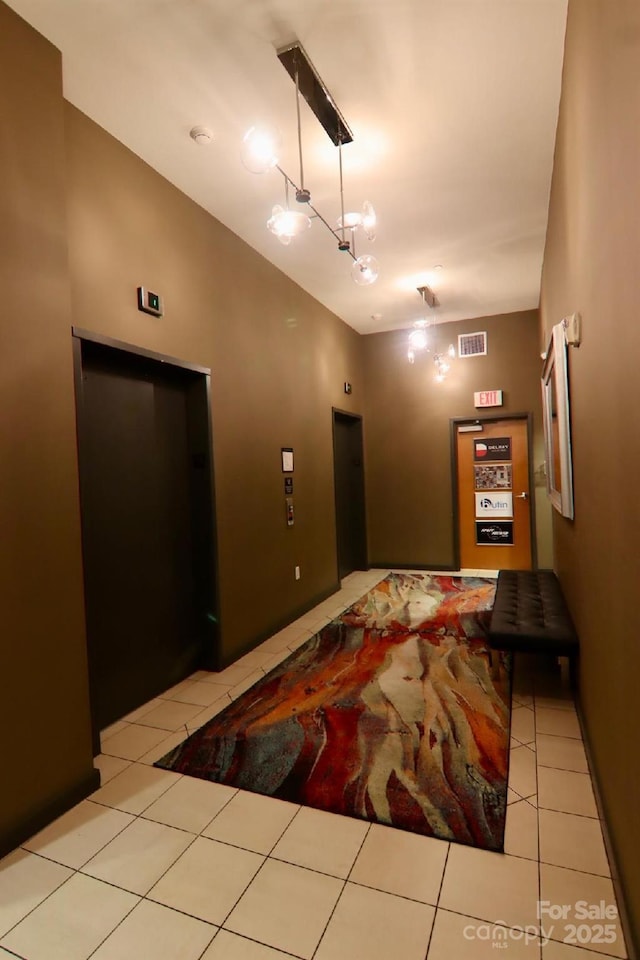 corridor featuring lofted ceiling, light tile patterned floors, and elevator