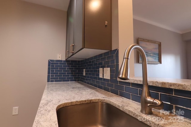 interior details with light stone countertops, sink, and decorative backsplash