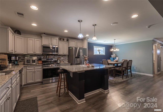 kitchen featuring a kitchen island, dark hardwood / wood-style floors, light stone countertops, appliances with stainless steel finishes, and ornamental molding