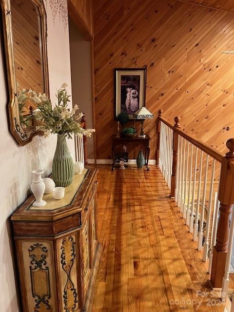 hall featuring light wood-type flooring and wooden walls