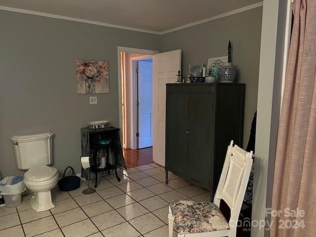 bathroom with crown molding, toilet, and tile patterned floors