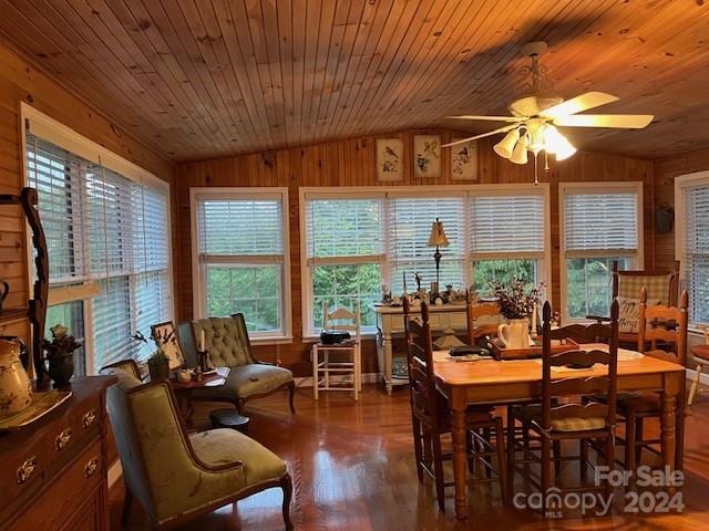 dining space with lofted ceiling, hardwood / wood-style flooring, ceiling fan, and wooden walls