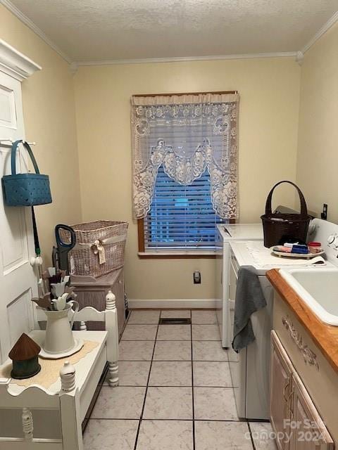 laundry room featuring washer and clothes dryer, light tile patterned floors, ornamental molding, cabinets, and a textured ceiling