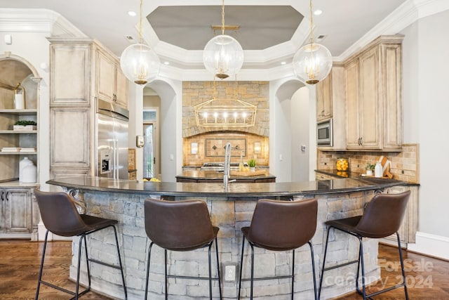 bar featuring backsplash, dark hardwood / wood-style flooring, hanging light fixtures, built in appliances, and crown molding