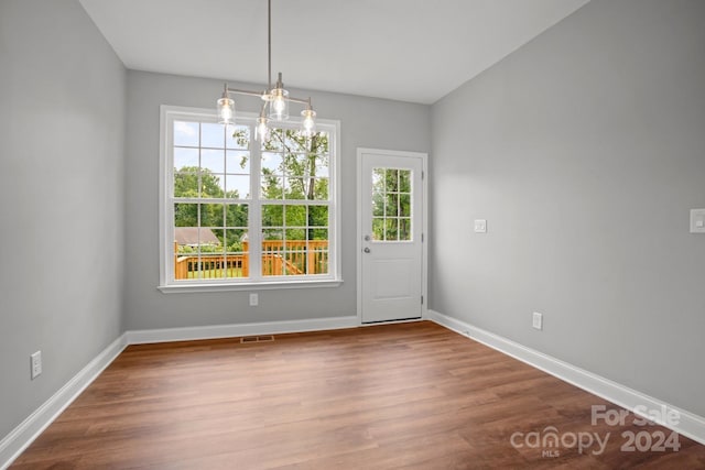 unfurnished dining area with plenty of natural light, wood finished floors, visible vents, and baseboards