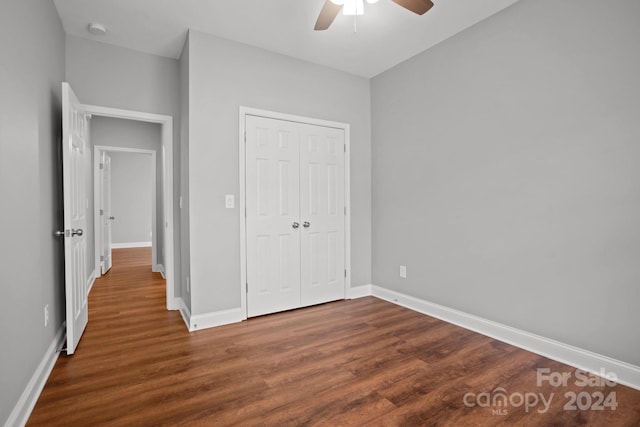 unfurnished bedroom with a closet, dark wood-style flooring, and baseboards