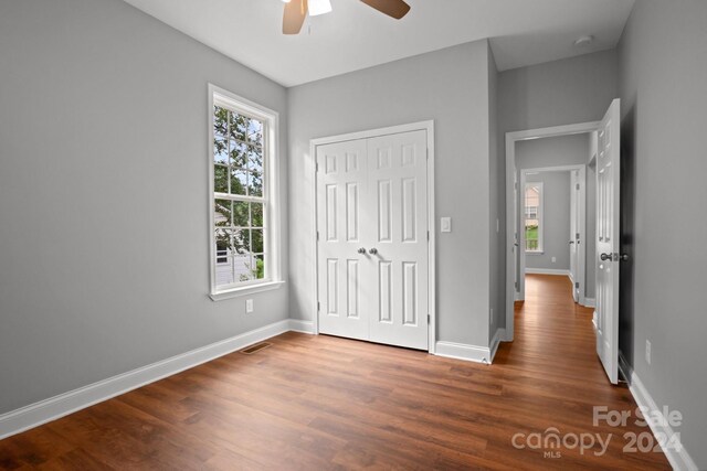 unfurnished bedroom with visible vents, a closet, baseboards, and wood finished floors