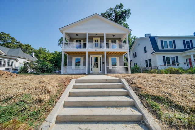 view of front of house featuring covered porch, a balcony, and french doors