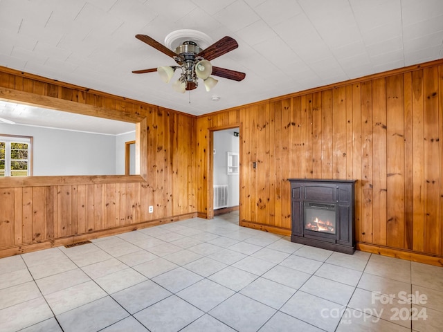 unfurnished living room with wood walls, ceiling fan, and light tile patterned flooring