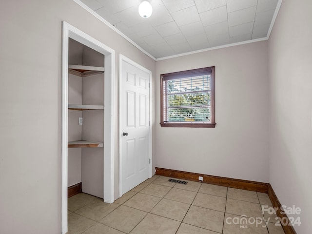 unfurnished bedroom featuring a closet, light tile patterned floors, and ornamental molding