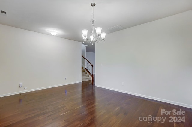 unfurnished room with a notable chandelier and dark hardwood / wood-style floors