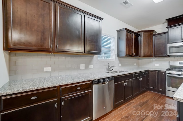 kitchen with sink, tasteful backsplash, dark brown cabinets, stainless steel appliances, and dark hardwood / wood-style flooring