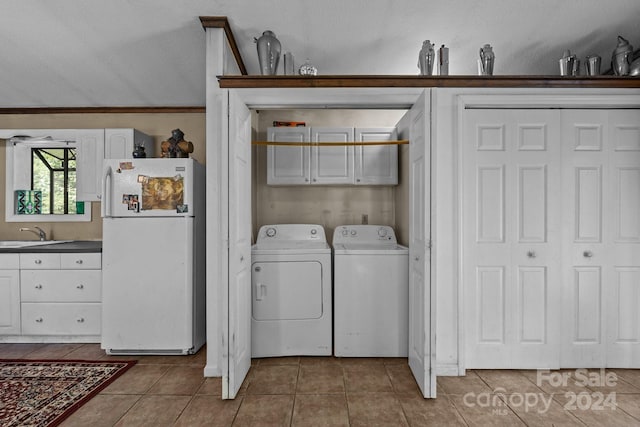 clothes washing area with tile patterned floors, sink, washer and dryer, cabinets, and a textured ceiling