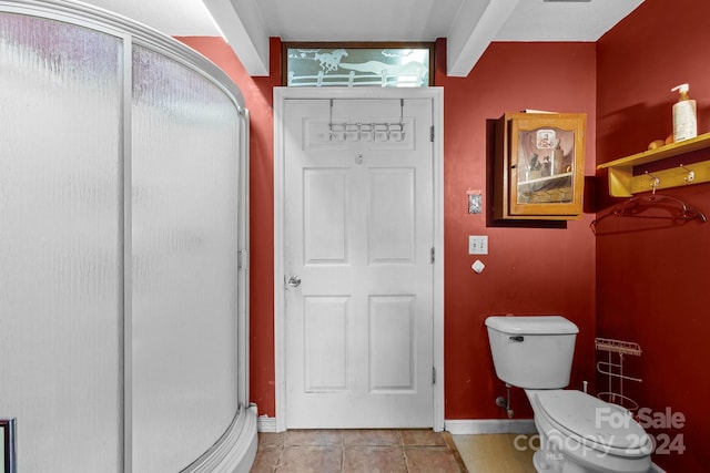 bathroom featuring toilet, an enclosed shower, and tile patterned floors