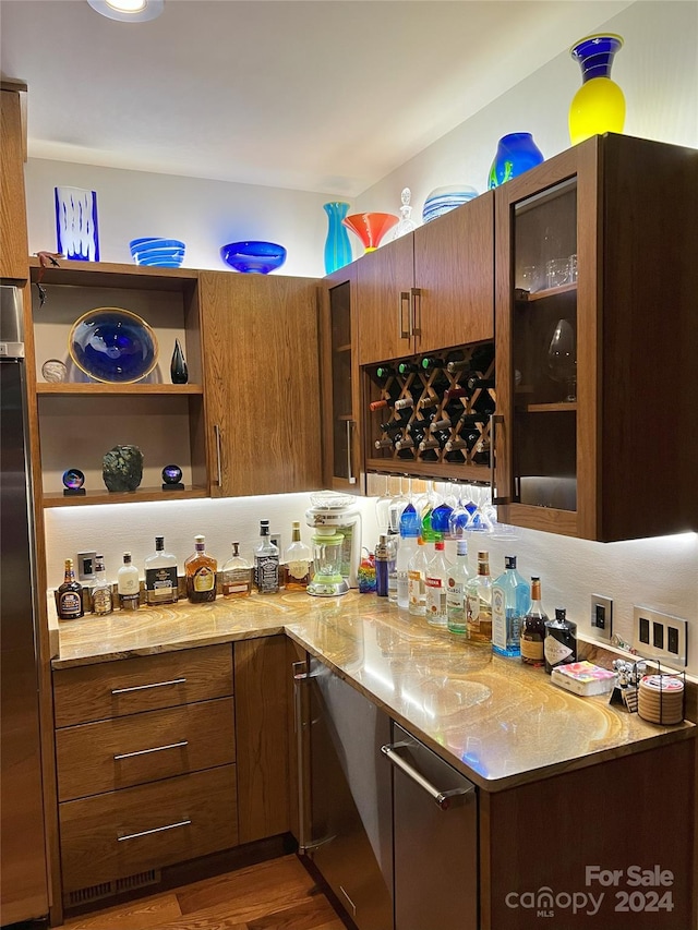 bar with dark hardwood / wood-style flooring, backsplash, and light stone countertops