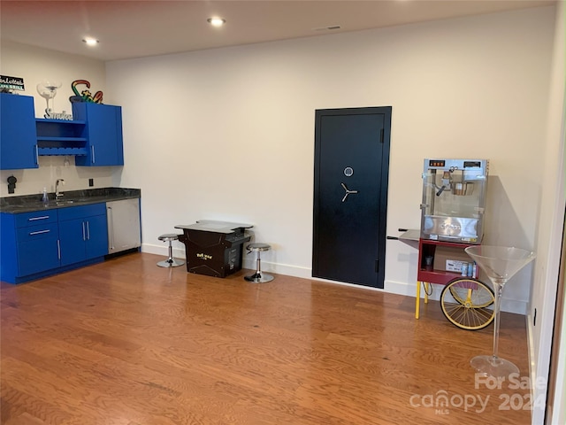 interior space with blue cabinets, hardwood / wood-style floors, and stainless steel dishwasher