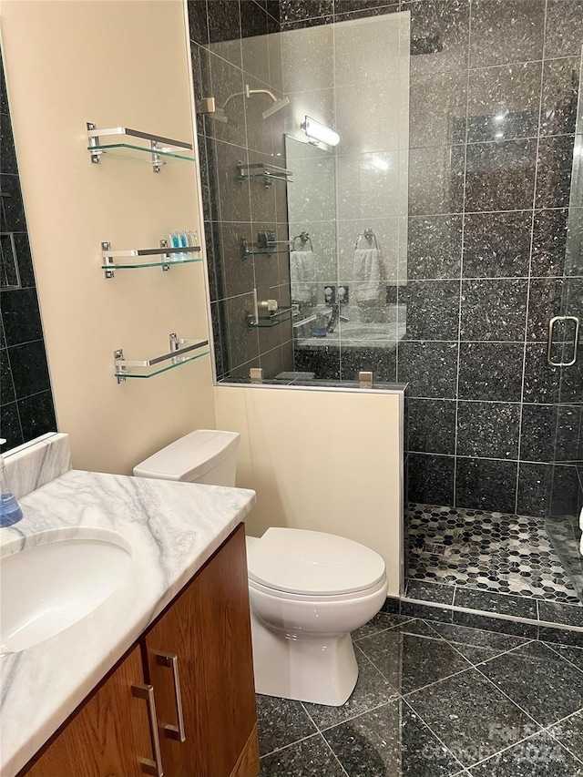 bathroom with toilet, vanity, tile patterned floors, and a tile shower