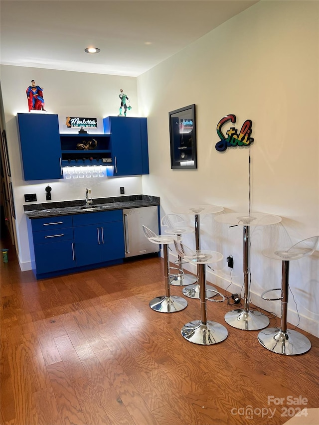 bar with dishwasher, sink, dark hardwood / wood-style flooring, and blue cabinets